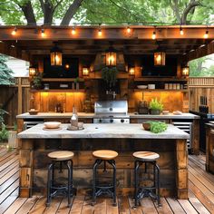 an outdoor kitchen with wooden floors and lights on the ceiling, along with stools