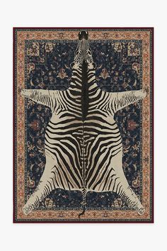 the zebra is standing on its hind legs in front of an area rug with floral designs