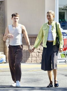 a man and woman walking down the street holding hands