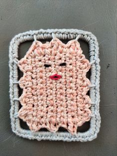 a crocheted square with a face on it