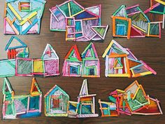 several houses made out of colored crayons on top of a wooden table next to each other