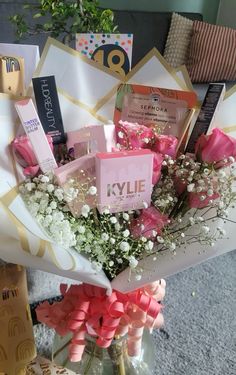 a vase filled with lots of pink and white flowers next to some cards on top of a table