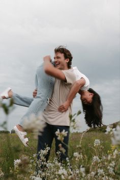 two people in a field with flowers and one person is holding the other's back