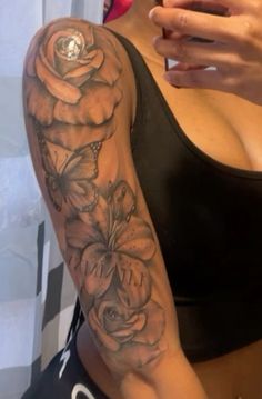 a woman's arm with flowers on it and a cell phone in her hand