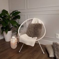 a white chair sitting on top of a wooden floor next to a potted plant