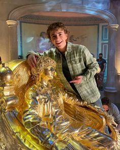 a man standing next to a golden statue