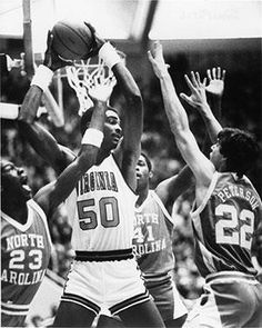 an old black and white photo of basketball players in the middle of a game with their hands up