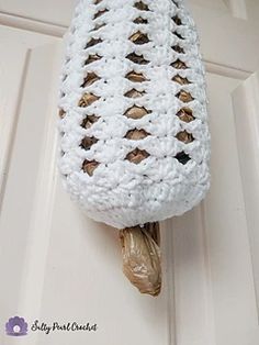 a white crocheted bag hanging on the door handle with a bird in it