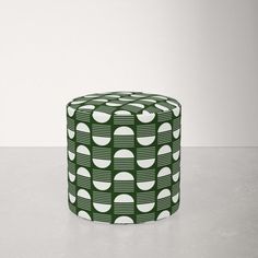 a green and white patterned stool sitting on top of a table next to a wall