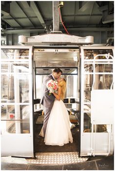 a bride and groom standing in the doorway of a train car with their arms around each other