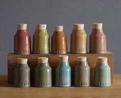 small bottles are lined up on a wooden shelf with cork top lids in different colors