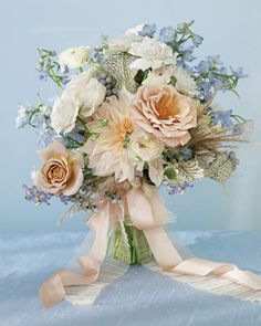 a bridal bouquet with flowers and ribbons on a blue tableclothed surface,