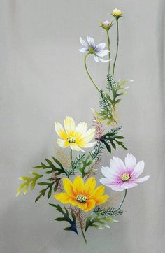 an arrangement of flowers in a vase on a white tablecloth with grey back ground