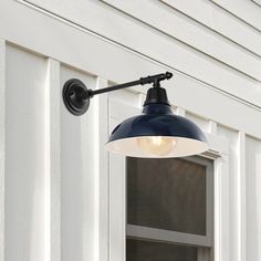 a black and white light hanging from the side of a building next to a window