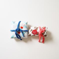 two wrapped presents are sitting next to each other on a white surface with blue and red bows