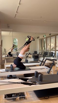 a woman is doing pivots on the treadmill in a large room with mirrors