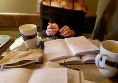 a woman sitting at a table with an open book and coffee cup in front of her