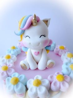 a cake decorated with an unicorn sitting on top of a flowery base and surrounded by flowers