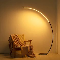 a chair with a blanket on it next to a light that is turned on by a lamp