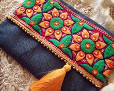 an embroidered clutch bag with tassels and beads on the front, sitting on a lace doily