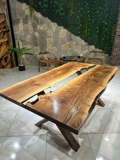 a table made out of wood sitting on top of a tile floor next to a stone wall