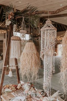 the table is set up with macrame hangings and plates on it, along with other decorations