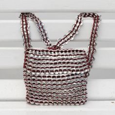 a red and white purse sitting on top of a white bench with chains hanging from it's sides