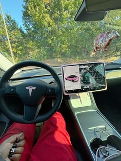 a person sitting in the driver's seat of a car while using a tablet