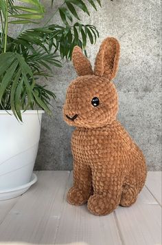 a stuffed rabbit sitting next to a potted plant