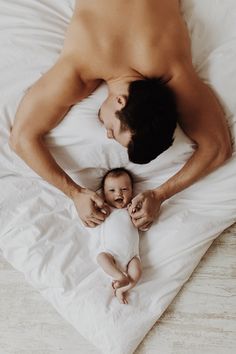 a man laying on top of a bed next to a baby