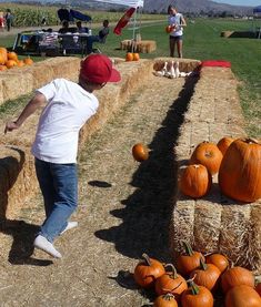 a young boy jumping over hay bales with pumpkins in the background