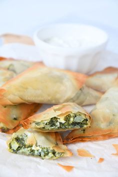 spinach and cheese stuffed pastries on a plate with dip in the bowl behind them