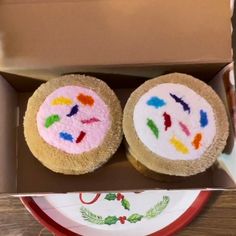 two decorated cupcakes sitting in a box on a table next to a plate