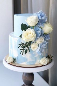 a blue and white wedding cake with flowers on top