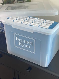 a plastic container with labels on it sitting on top of a dresser next to a potted plant