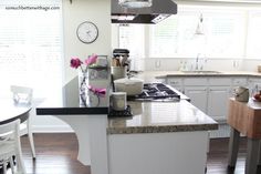 a kitchen with white cabinets and an island in front of a stove top oven next to a dining room table