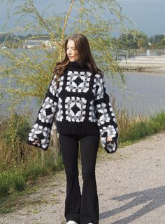 a woman in black and white sweater walking down the street with her hands on her hips