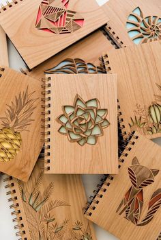 several wooden notebooks with designs on them and pineapples in the middle one is made out of wood