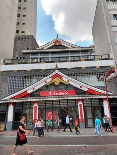 people are walking in front of a building with red and white trims on it