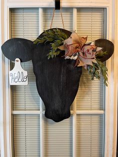 a cow's head hanging on the front door with a name tag attached to it