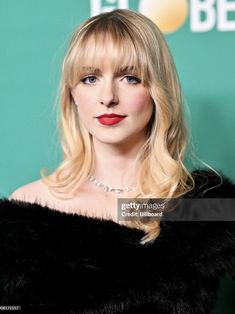 a woman with long blonde hair wearing a black dress and red lipstick, posing for the camera