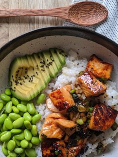 a bowl filled with rice, meat and vegetables next to an avocado slice