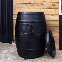 a large black barrel sitting next to a window on the side of a wooden building