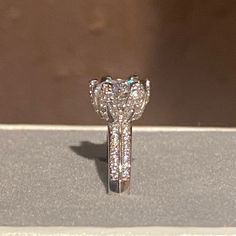 a diamond ring sitting on top of a display case with other jewelry items in the background