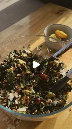 a glass bowl filled with chopped vegetables on top of a wooden table next to a spoon