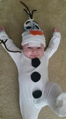 a baby in a snowman costume laying on the floor with his arms out and eyes closed