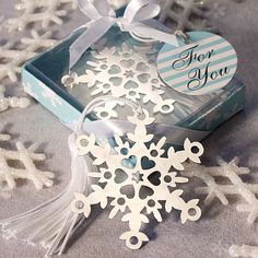 a snowflake ornament in a gift box with a tag on it