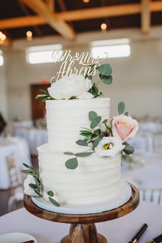 a white wedding cake with greenery on top