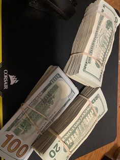 two stacks of money sitting on top of a mouse pad next to a computer keyboard