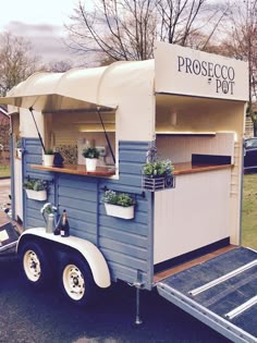 a food truck is parked on the side of the road with potted plants in it